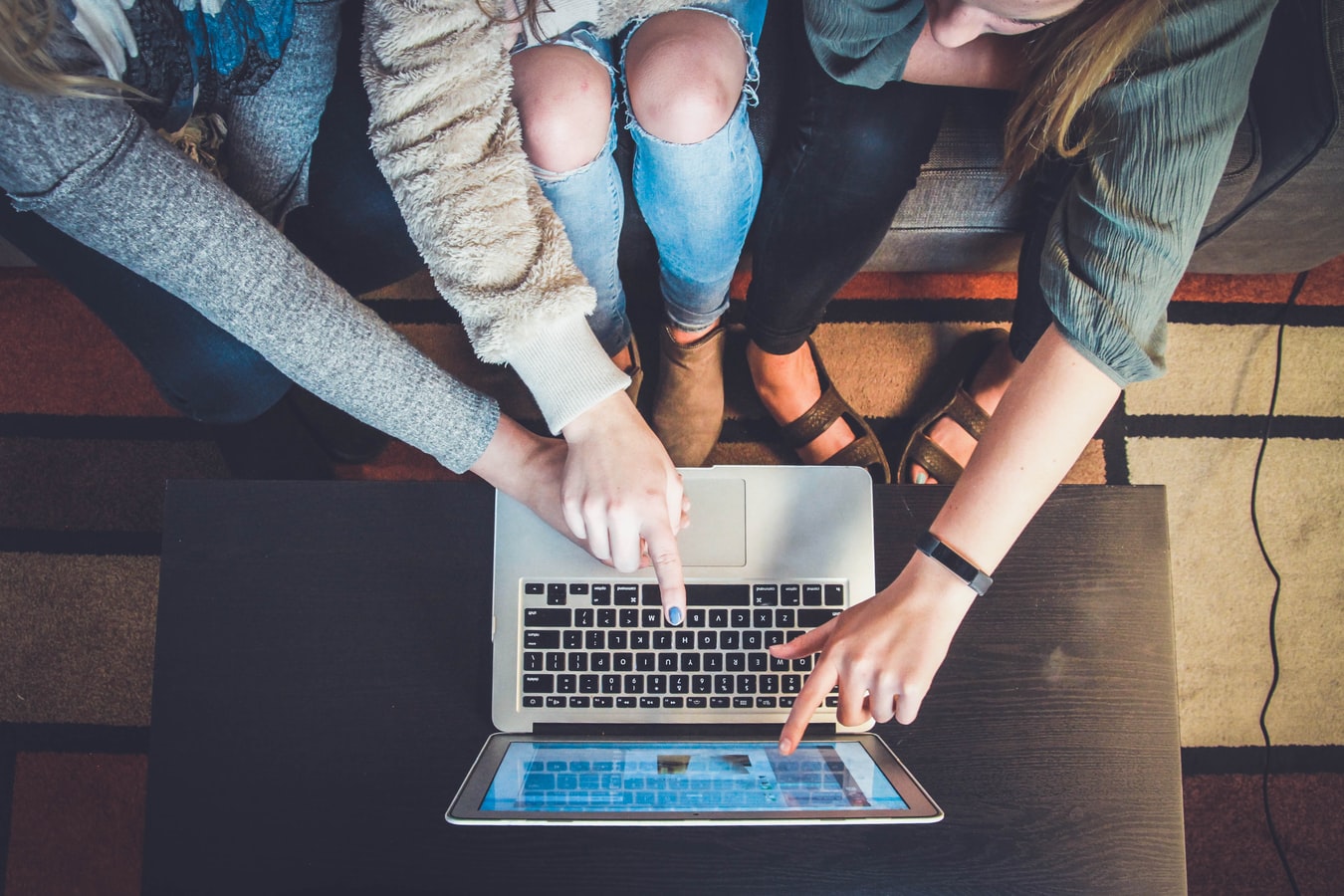 Three people pointing at social media posts on a laptop screen